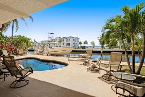 a patio with chairs and a pool and a boat at Sombrero Beach Retreat in Marathon