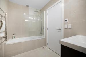 a bathroom with a shower and a tub and a sink at Remarkables Retreat Apartment in Queenstown