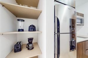 a kitchen with a refrigerator on a shelf at Menesse Midtown 2 Unit 208 in Playa del Carmen