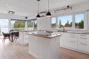 a kitchen with white cabinets and a table with chairs at Naramata paradise! Huge Pool & Deck, Families Welcome! in Naramata