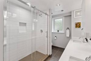 a white bathroom with a shower and a sink at Naramata paradise! Huge Pool & Deck, Families Welcome! in Naramata