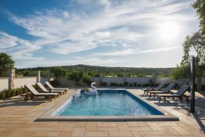 a swimming pool with lounge chairs and a swimming poolvisor at Family friendly house with a swimming pool Primosten Burnji, Primosten - 21068 in Primošten