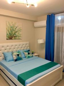 Schlafzimmer mit einem Bett mit blauen und grünen Kissen in der Unterkunft Condo Near Mactan Airport in Cebu City