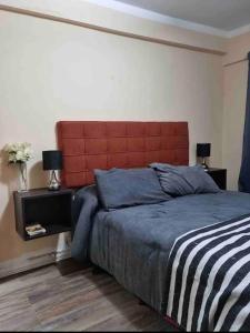 um quarto com uma cama grande e uma cabeceira vermelha em Lindo departamento pleno centro. em San Fernando del Valle de Catamarca