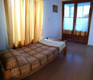 a bed in a room with a large window at Amplia casa con estacionamiento in Esquel