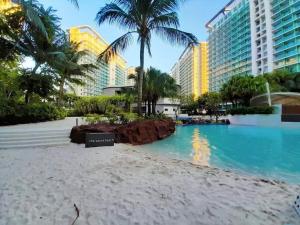 a resort swimming pool with palm trees and buildings at Azure - Acqua Apartments in Manila