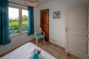 a bedroom with a bed and a window and a chair at Rêve de Palmier in Le Gosier +17 photos