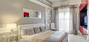 a white bedroom with a bed and a television at SuiteHome Taormina in Giardini Naxos