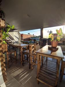 un patio con mesas de madera y sillas en el balcón en Como en casa Hostel en Posadas