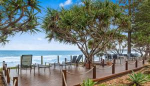 a wooden deck with chairs and the beach at Nautical Owl 122 Nautilus Beach Resort in Coffs Harbour