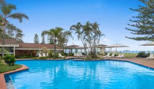 a swimming pool in a resort with palm trees at Nautical Owl 122 Nautilus Beach Resort in Coffs Harbour