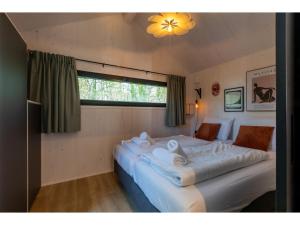 een slaapkamer met 2 bedden met witte lakens en een raam bij Enjoy a holiday in the cozy Tiny house on the edge of the forest and the dunes! in Zoutelande