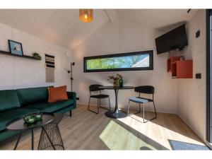 sala de estar con sofá verde y mesa en Enjoy a holiday in the cozy Tiny house on the edge of the forest and the dunes!, en Zoutelande