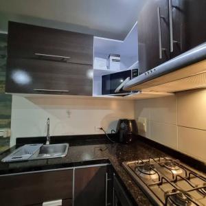 a kitchen with a stove top and a sink at Ardival apartment - WAIWA HOST in Bucaramanga