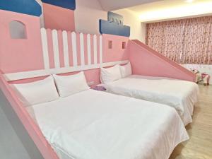 2 camas en una habitación rosa y blanca en 拾光悠宿, en Yuli