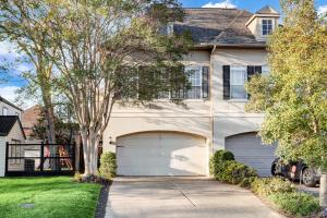 a house with two garage doors in a yard at Spacious & Intimate Townhome near TMC/NRG Stadium/Rice Village in Houston