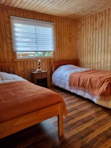 a bedroom with two beds and a window in it at Cabañas Antü Küyen Melipeuco in Melipeuco