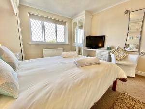 a large white bed in a room with a tv at Heidaway - Padstow in Padstow