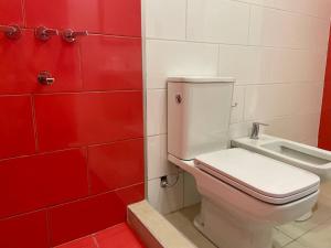 a bathroom with a white toilet and red tiles at Duplex Renovado in San Juan