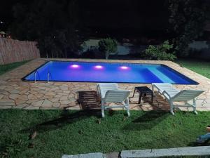 - un groupe de chaises et une piscine la nuit dans l'établissement Piscina Climatizada - Chácara em Condominio, à Ibiúna