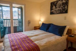 1 dormitorio con 1 cama grande y balcón en Hostal Corihuasi, en Cusco