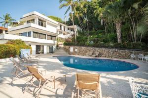 un grupo de sillas y una piscina frente a una casa en Gran habitacion con terraza vista espectacular, piscina en Acapulco