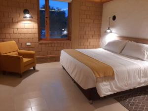 a bedroom with a bed and a chair and a window at La Alhambra Hotel Boutique in Villa de Leyva