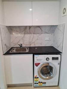 a kitchen with a sink and a washing machine at Private & Cosy Two Storey Guest House in Guildford