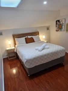 a bedroom with a large bed with white sheets and two lamps at Private & Cosy Two Storey Guest House in Guildford