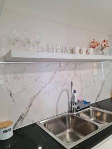 a kitchen with a sink and wine glasses on a shelf at Private & Cosy Two Storey Guest House in Guildford