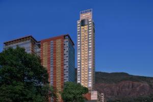 two tall buildings with trees in front of a mountain at Marriott Executive Apartments Navi Mumbai in Navi Mumbai