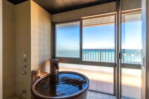 a bathroom with a tub with a view of the ocean at Meijikan in Izu