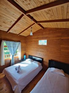 Duas camas num quarto com paredes de madeira em Cabañas Barú Dota em Santa María