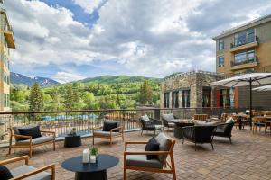 a patio with tables and chairs with mountains in the background at The Westin Riverfront Resort & Spa, Avon, Vail Valley in Avon