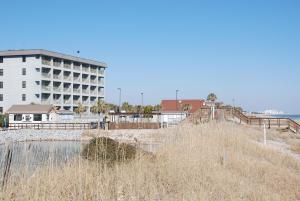 a building on the beach with tall brown grass at Myrtle Beach Resort by Beach Vacations in Myrtle Beach