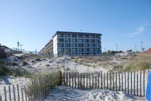 a building on the beach with a fence in the sand at Myrtle Beach Resort by Beach Vacations in Myrtle Beach