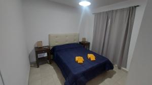 1 dormitorio con 1 cama azul y 2 zapatillas amarillas. en Departamento Salta en Mendoza