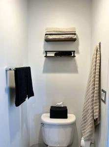 een witte badkamer met een wit toilet en handdoeken bij Tokyo in Denver, Speakeasy Room & Skyline Rooftop In Central RiNO in Denver