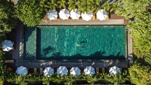 einen Blick über den Pool mit einer Person im Wasser in der Unterkunft Mulberry Collection Silk Village in Hoi An