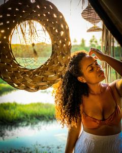 a woman is standing next to a window at Flor da Aldeia Eco Hospedaria in Camaçari