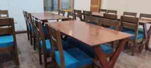 a row of wooden tables and chairs in a room at Lynx near Leh airport in Leh