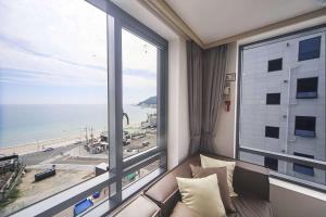 a room with a couch and a large window at Hound Hotel Songjeong in Busan