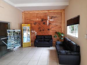 una sala de estar con 2 sofás de cuero y una pared en Hotel Beira Rio, en Aquidauana