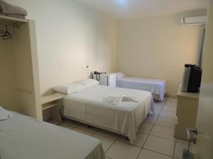 a hotel room with two beds and a television at Hotel Beira Rio in Aquidauana