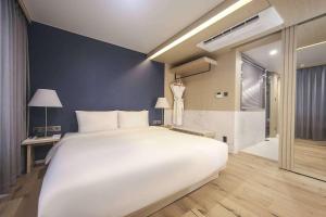 a bedroom with a large white bed and a bathroom at Hound Hotel Songjeong in Busan