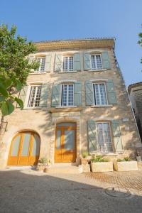 duży kamienny budynek z brązowymi drzwiami i oknami w obiekcie La Maison de Beaumont w mieście Beaumont-de-Pertuis