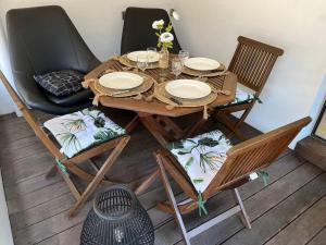 una mesa de madera y sillas con platos. en Studio tropical baie des citrons, en Noumea