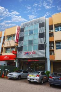 新山的住宿－GODORI HOTEL SDN BHD，两辆汽车停在大楼前