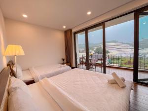 sypialnia z 2 łóżkami i dużym oknem w obiekcie The Green House Villa w mieście Da Lat