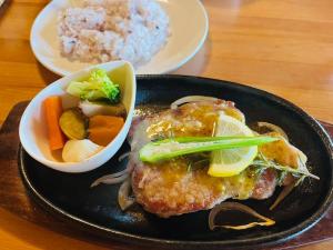 um prato de alimentos com carne e legumes sobre uma mesa em Kurokawa Marigold em Minamioguni